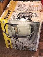 Boxed Bissel deep cleaning carpet and upholstery machine, model 1655C, showing machine illustration, with manual on top and taped box edges.