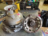 Metal burner and fuel tank on workbench, showing red valve and metal frame of burner.