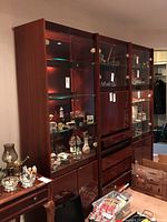 Front and angled view of the cabinet showing glass door sections with displayed collectibles and the bottom solid doors.