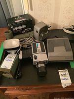 Photo showing all items in the lot including boxed car camera, flashlight, Keystone Capri movie camera, Polaroid Spectra System camera, and flash unit.