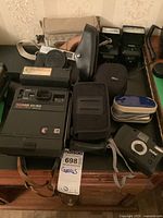 Wide shot of all vintage cameras and accessories including Kodak EK160, Vivitar camera, Coronet Canon with case, two flashes, light meter, and various cases