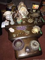 Wide view of 21 home decor items on a wooden tiered table including candle holders, amethyst grapes, glass and ceramic decor.