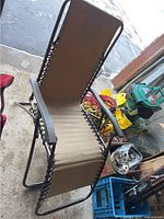 Side view of beige Zero Gravity chair with metal frame, fabric seating, armrests and reclining function.