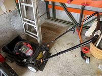 Full side view of Remington push lawn mower showing handle, body, wheels, and grass catcher attachment in garage setting.