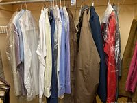 Clothing rack with leather jacket and multiple long-sleeve shirts of various colors hung on hangers.
