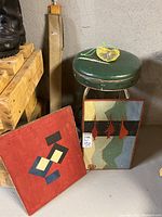 Overall view showing green vinyl stool, two paintings propped on floor and drafting square case behind