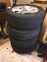 Four stacked tire and rim assemblies in garage setting