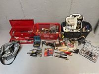 Wide view of assorted tools and toolboxes including rotary tool kit, vise, pliers, screwdrivers, engraver, magnetic window cleaner, rasp, socket set, and storage containers.