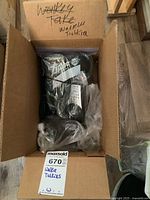 Top-down photo inside an open cardboard box showing multiple small electronic devices packed in plastic bags.