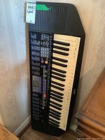 Full view of the Yamaha keyboard resting upright displaying 38 keys, control panel with labeled buttons and LCD screen, black plastic housing with visible signs of wear.