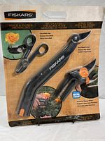 Front view of the packaged Fiskars Shrub & Flower Pruning Set showing all three tools labeled and visible in closed packaging.