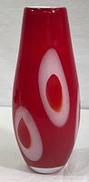 Front view of tall red glass vase with white oval shapes and red centers showing shape and decoration