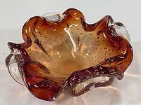 Top and angled view showing the amber bronze color incorporating suspended bubbles with clear glass edges and undulating shape of the bowl.