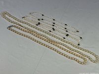 Three strands of pearl necklaces laid flat showing pearls and clips.