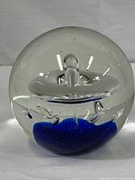 Front view of the solid crystal and cobalt hand blown art globe showing clear glass top with cobalt blue base and internal air bubbles.
