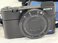 Front view of black Sony Cyber-shot DSC-RX100 camera showing Carl Zeiss Vario-Sonnar T* lens