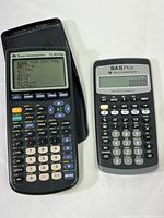 TI-83 Plus and BA II Plus calculators shown side by side on a white surface, TI-83 Plus screen displays menu, both calculators powered on.
