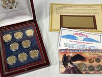 Overview photo showing the wood box with coin sets, Americana Series Coin Set with multiple presidential coins, and Danbury Mint $1000 Treasury Note facsimile with certificate.
