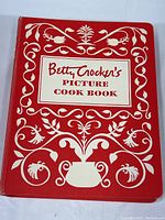 Red hardcover binder with white floral design and title on front cover.