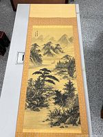 Full view of the vintage Chinese scroll painting laid out on table, showing entire scroll with landscape scene of mountains and water.