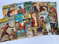 12 vintage Classics Illustrated comic books spread and stacked, titles visible including Two Years Before The Mast, Kidnapped, and The Deer Slayer.
