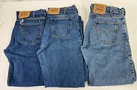 Three pairs of Levi's 505 jeans laid flat showing back pockets and branding with varying denim shades.