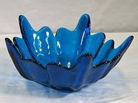 Front angled view showing the flower petal shape and glossy cobalt blue color of the glass bowl.