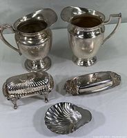 Wide view showing the full set with two large pitchers, two covered butter dishes, and one small shell-shaped dish.