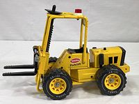Side view of vintage yellow Tonka toy forklift showing forks, wheels and body detail.