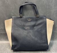Front view of black and beige Kate Spade handbag on neutral background