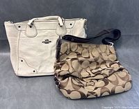 Front view of both COACH bags showing white leather tote and brown signature canvas hobo bag in good condition