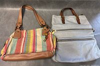 Two Fossil handbags side by side on a gray surface, showing overall design and color.