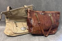 Two Fossil bags shown together on grey background, one beige with zip pocket, one brown faux crocodile pattern.