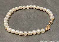 Full bracelet view showing round freshwater pearls and gold clasp detail.