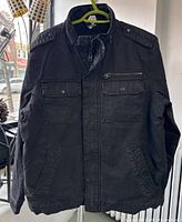 Front view of black denim Levi's sherpa jacket hanging on hanger showing overall condition and design including chest and hand pockets