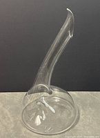 Photo showing clear curved crystal decanter against dark background to highlight shape and clarity.