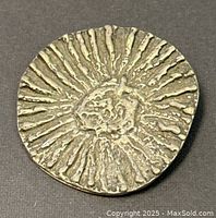 Front view of round silver brooch with textured radiating line design.