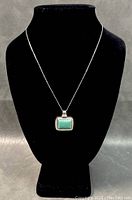 Front view of vintage necklace on black display bust, showing 18 inch box-style sterling silver chain and square turquoise pendant.