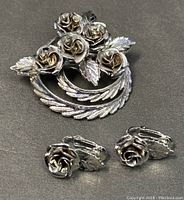 Front view of CORO brooch and matching clip-on earrings showing detailed rose and leaf design in silver-tone metal.
