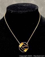 Front view of Givenchy necklace displayed on black velvet bust showing gold-tone chain and geometric black and gold pendant