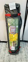 Packaged Coleman instant screened canopy tent in a green carrying bag with red straps and wheels.