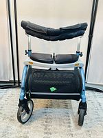 Front view of Evolution Xpresso Zero medical walker showing thick padded split seat, padded backrest, and large 8-inch front wheels.