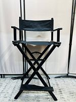 Front view of black folding chair showing seat, backrest, and armrests