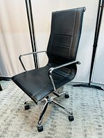 Front angled view of the black leather high back office chair with chrome arms and base showing seat, cushion and wheels.
