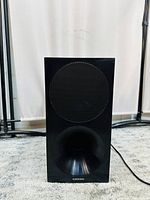 Front view of the black Samsung wireless subwoofer showing the speaker grille and bass port.