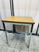 Side view of the rectangular table showing wood grain laminate top and metal legs