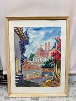 Frontal photo showcasing the colorful watercolor painting with architectural and natural elements framed with a light wood frame and white mat.