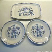 3 pieces of ceramic dish set with blue floral and character designs: 2 round plates and one rectangular platter.