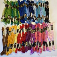 Overall image showing all 50 DMC embroidery floss skeins in various colors including green, blue, purple, red, pink, yellow, brown, and black.