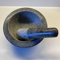 Top-down view showing mortar bowl with pestle inside, highlighting grey mottled stone texture and deep bowl shape.